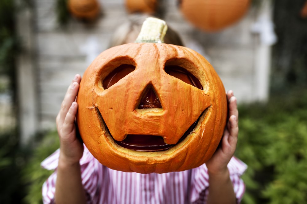 Child holding carved pumpkin